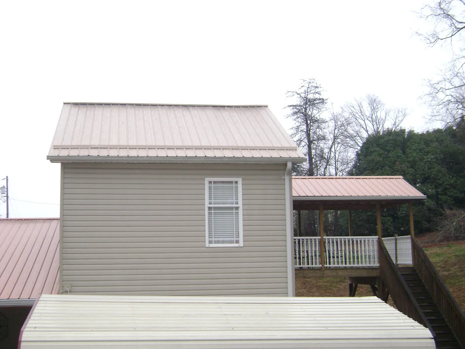 Tan metal roofs on a two story addition and attached porch, from a Roof Replacement job in Fruitland